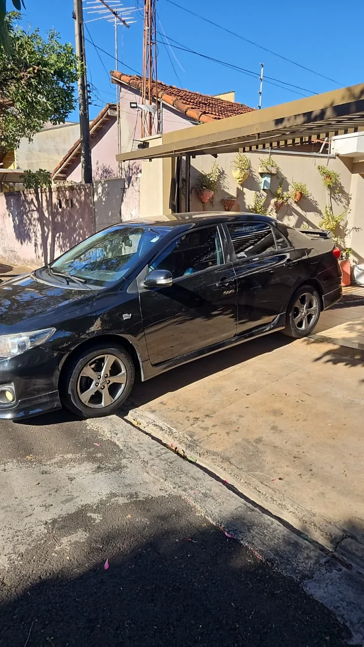 Corolla sedã preto fotografado de lado, com o veículo inteiro visível.