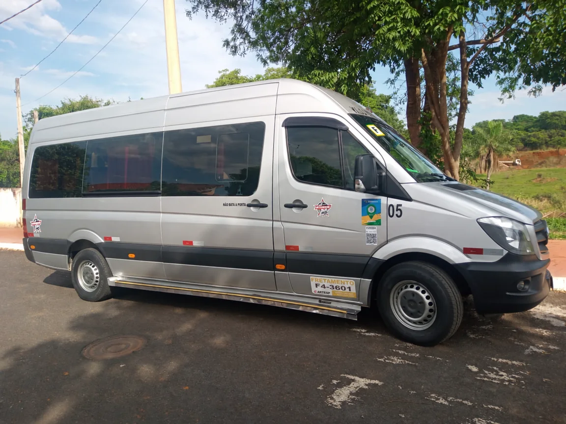Van prata parceira estacionada à sombra de árvores.